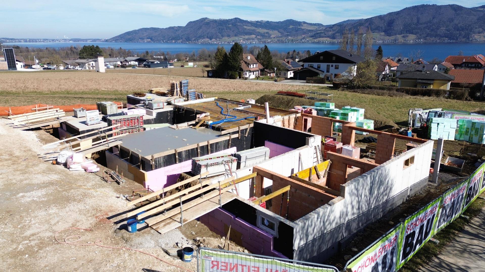 Baustelle mit bereits errichteten Wänden und Blick auf den See und die Berge.
