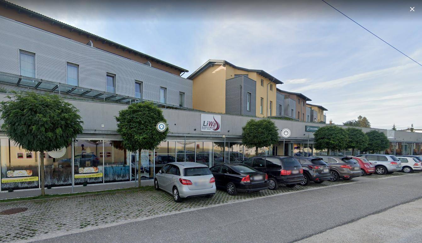 Breite Ansicht der modernen Geschäftszeile mit verschiedenen Ladenlokalen und darüberliegenden Wohneinheiten.