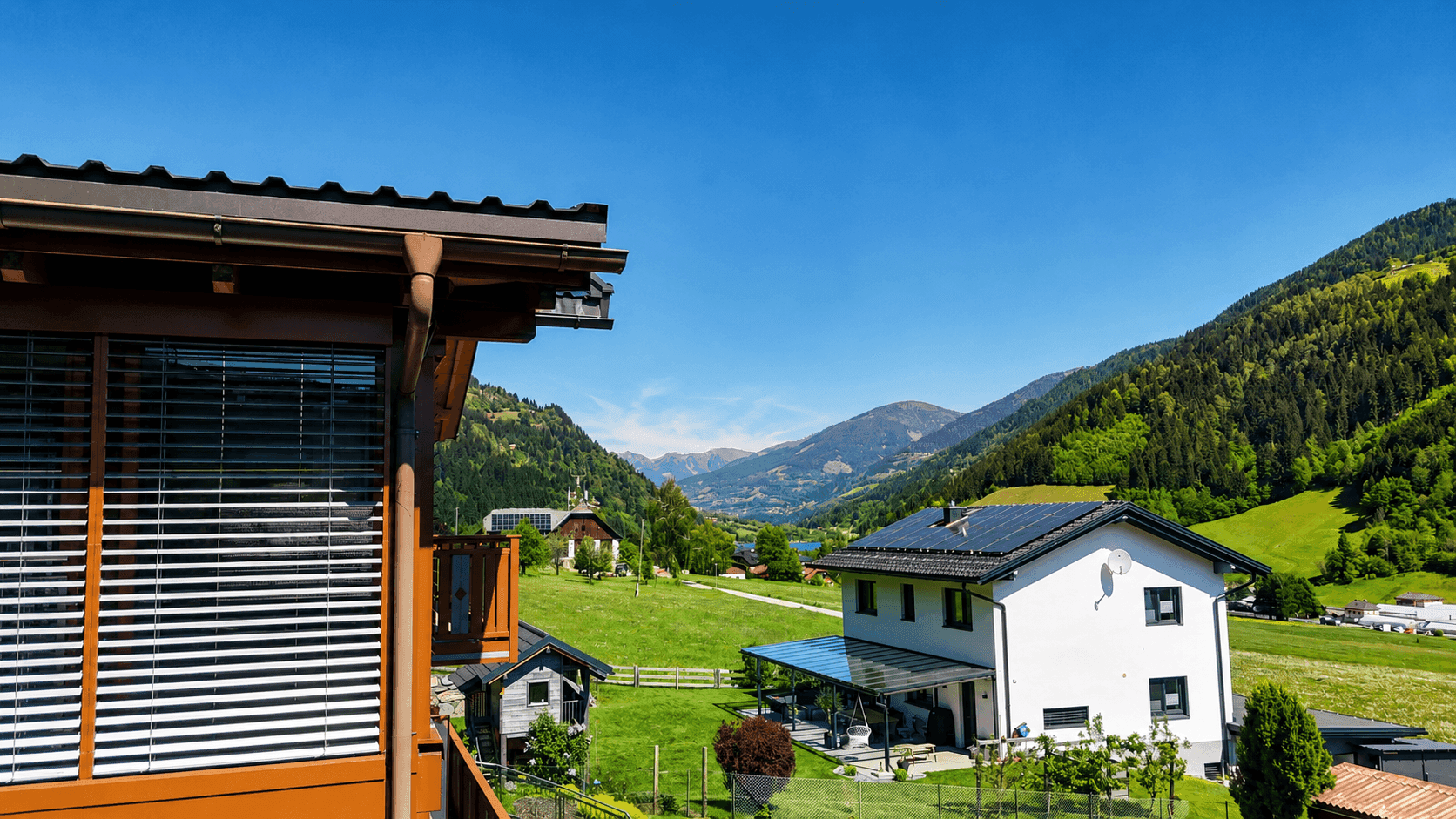 Panoramablick auf die Berglandschaft mit einem See und umliegenden Häusern.