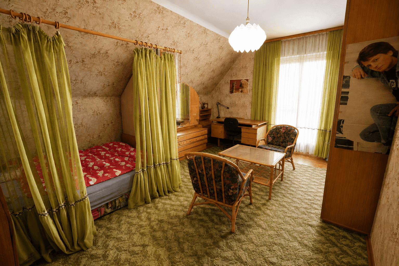 Dachschlafzimmer mit Einzelbett, Rattanmöbeln, gemusterter Tapete und Teppichboden.