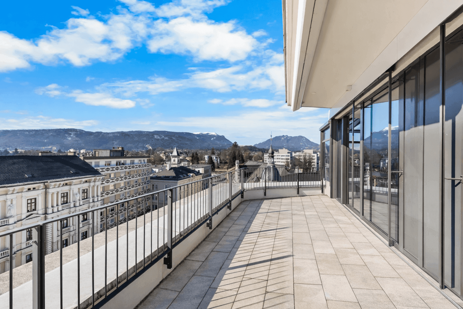 Weitläufige Terrasse mit Blick auf die historische Stadtarchitektur und die umliegende Berglandschaft.