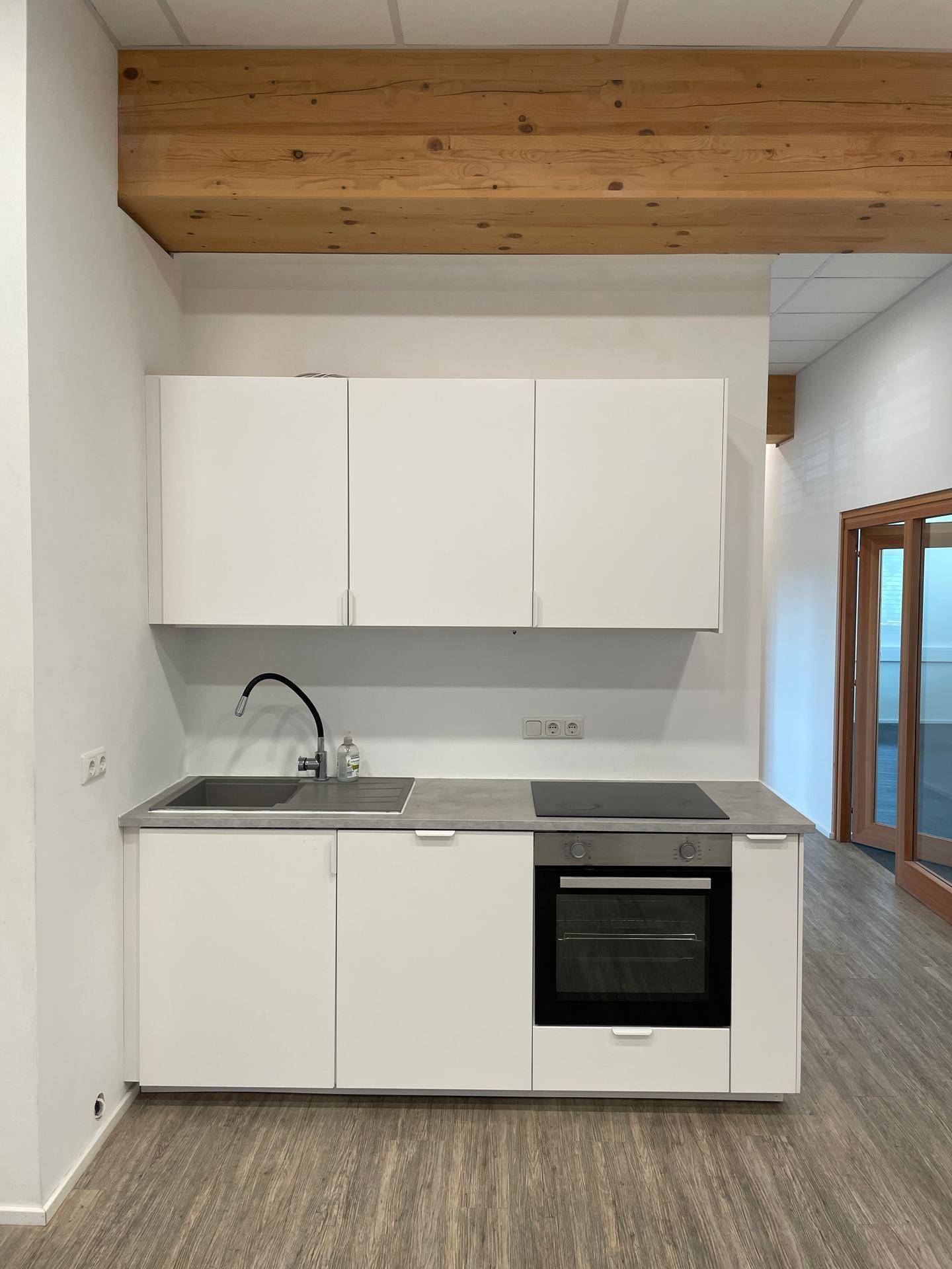 Moderne Küchenzeile mit weißen Schränken, Spüle, Backofen und Induktionskochfeld.