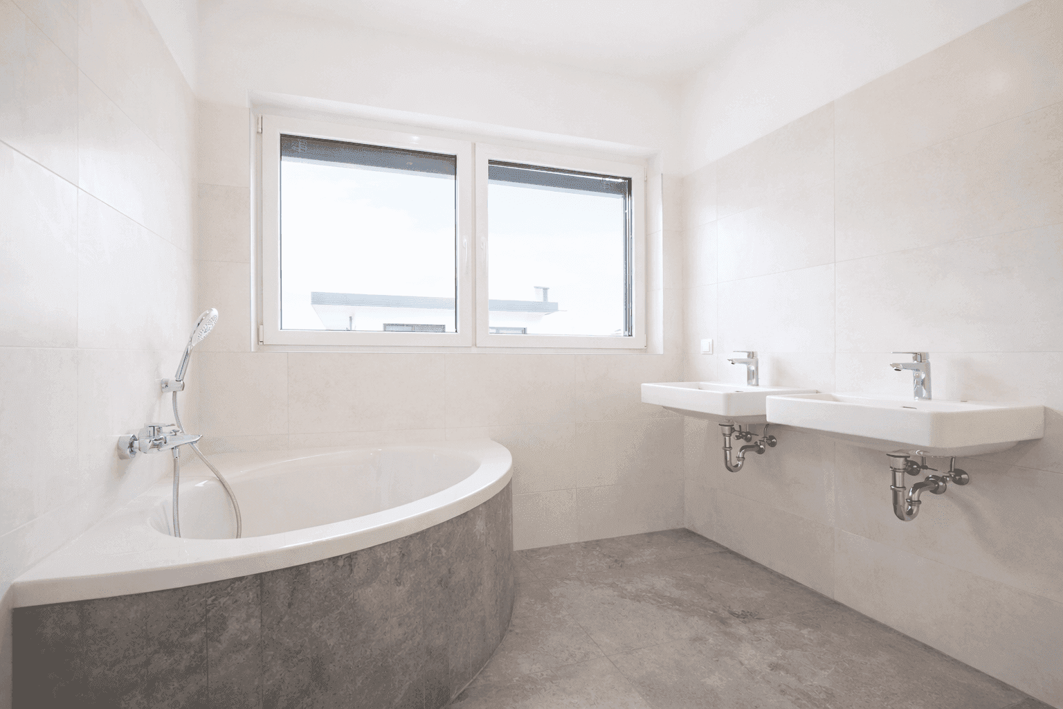 Modernes Badezimmer mit Eckbadewanne, Doppelwaschbecken und großen Fliesen.