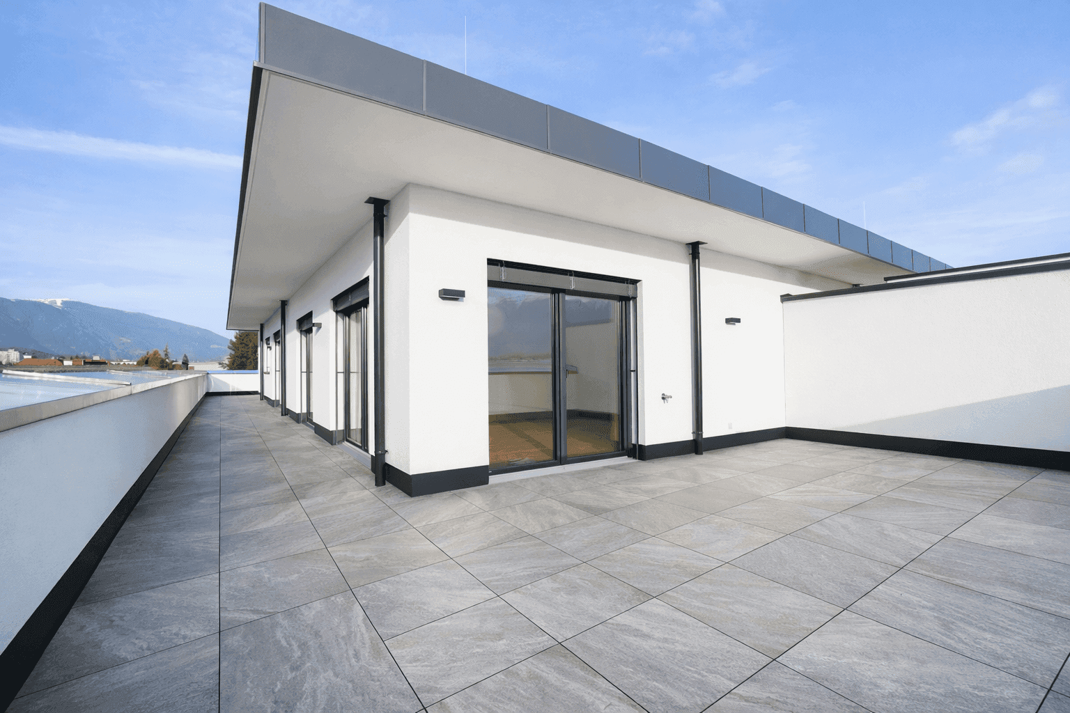 Moderne Architektur mit großer Dachterrasse und weitem Blick auf die Umgebung.