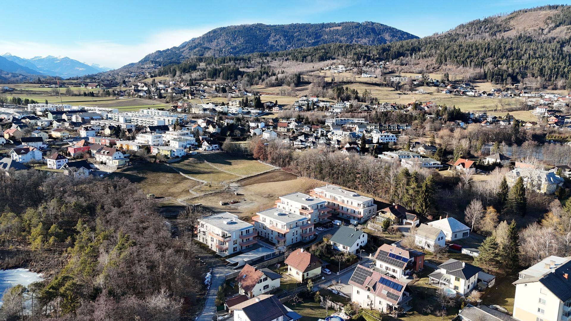 Panoramablick aus der Vogelperspektive auf eine ländliche Wohngegend mit Bergen und viel Grün.