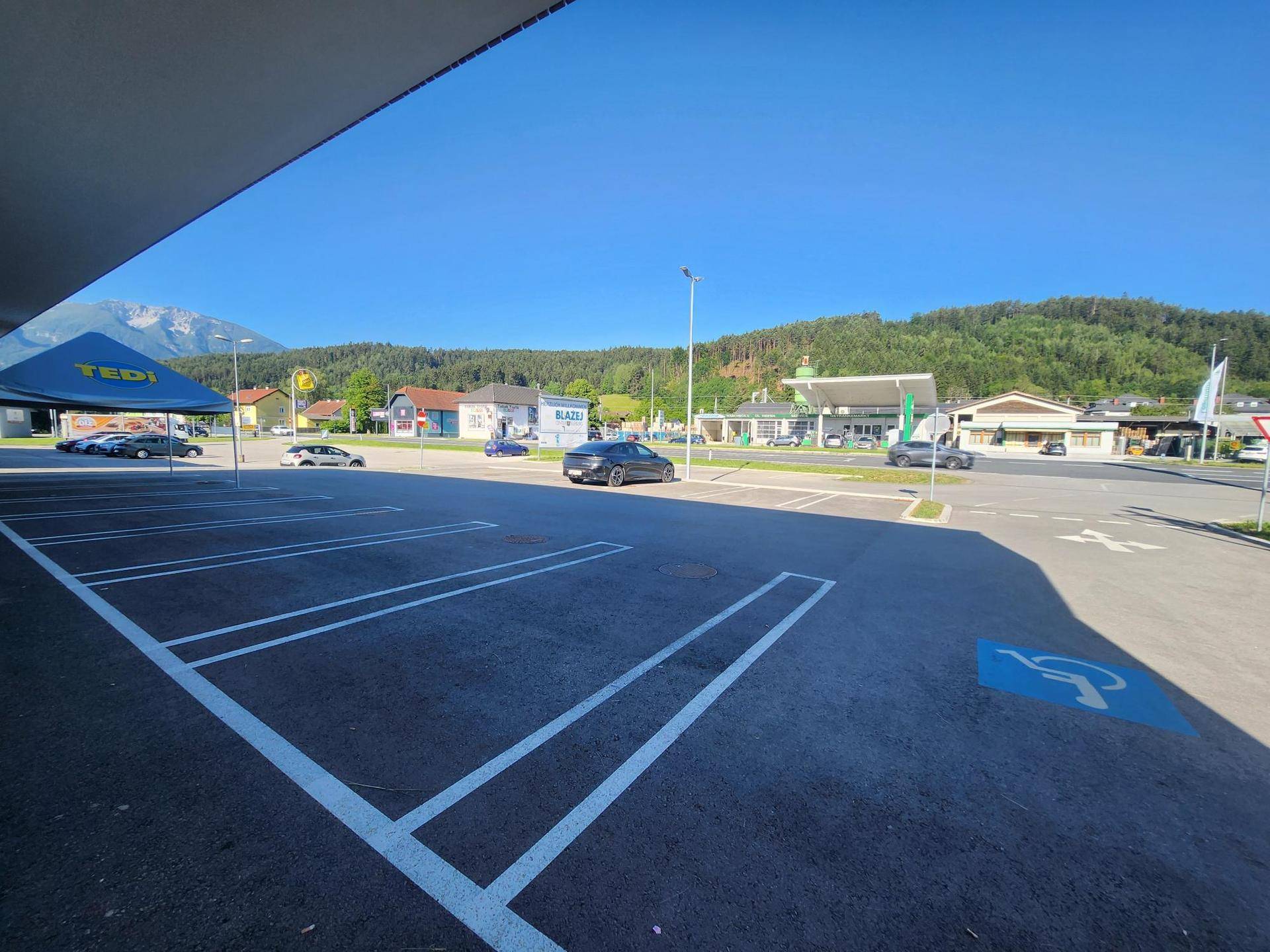 Großer Parkplatz vor einem Geschäftsgebäude mit Blick auf die umliegende Landschaft und Berge im Hintergrund.