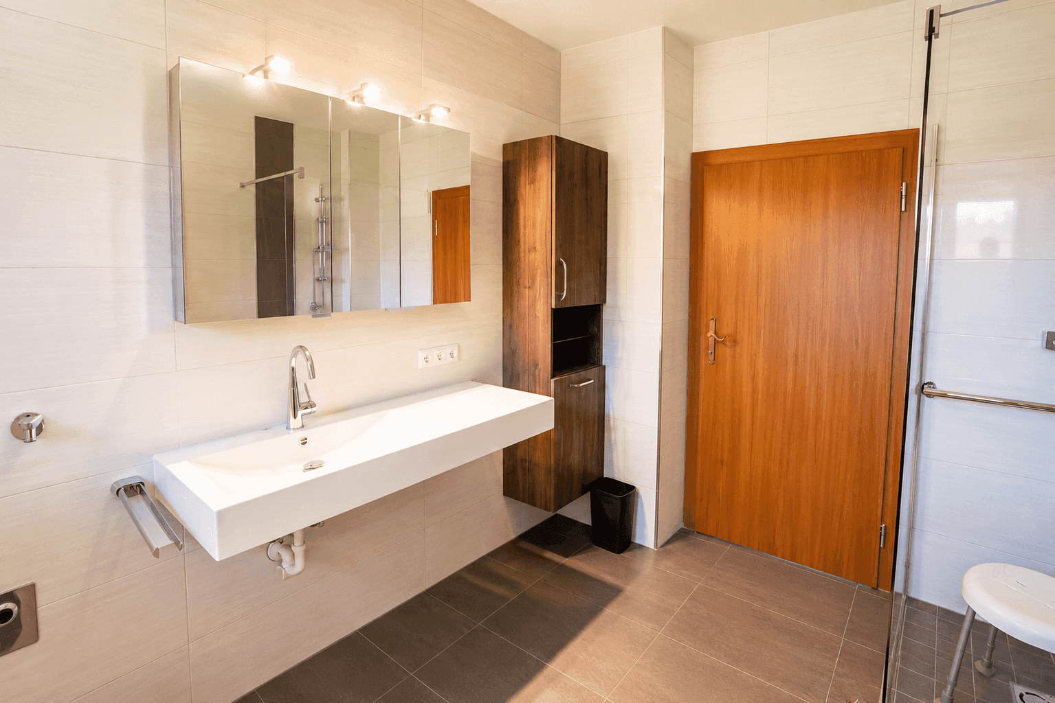 Modernes Badezimmer mit barrierefreier Dusche, großem Waschtisch und Wand-WC.