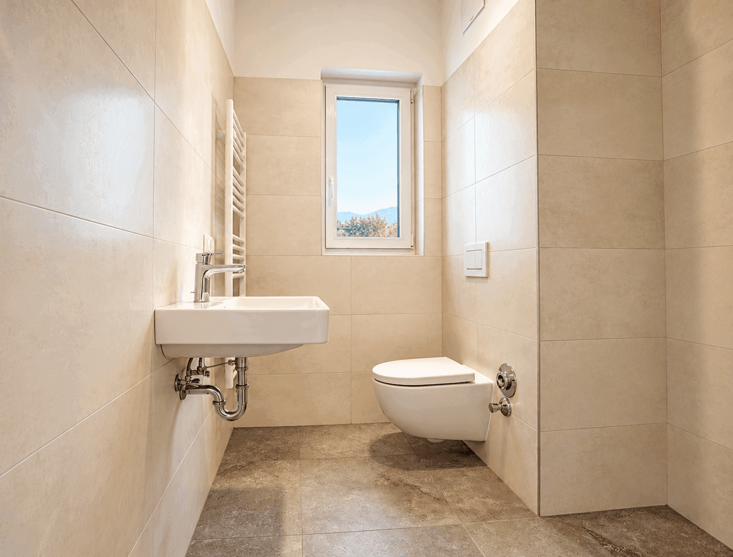Helles Badezimmer mit Einzelwaschbecken, wandhängendem WC und Fenster, gefliest.