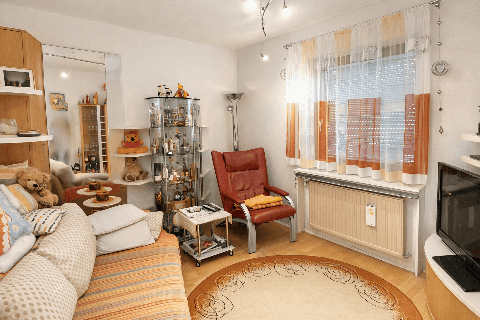 Gemütliches Wohnzimmer mit Parkettboden, beiger Couch und einem Sessel in Terrakotta.