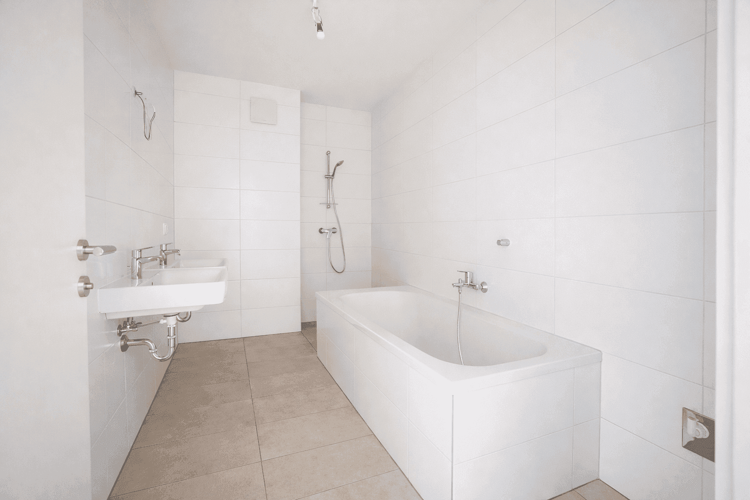 Modernes Badezimmer mit Badewanne, Dusche und weißen Fliesen, ausgestattet mit zeitgemäßen Armaturen.