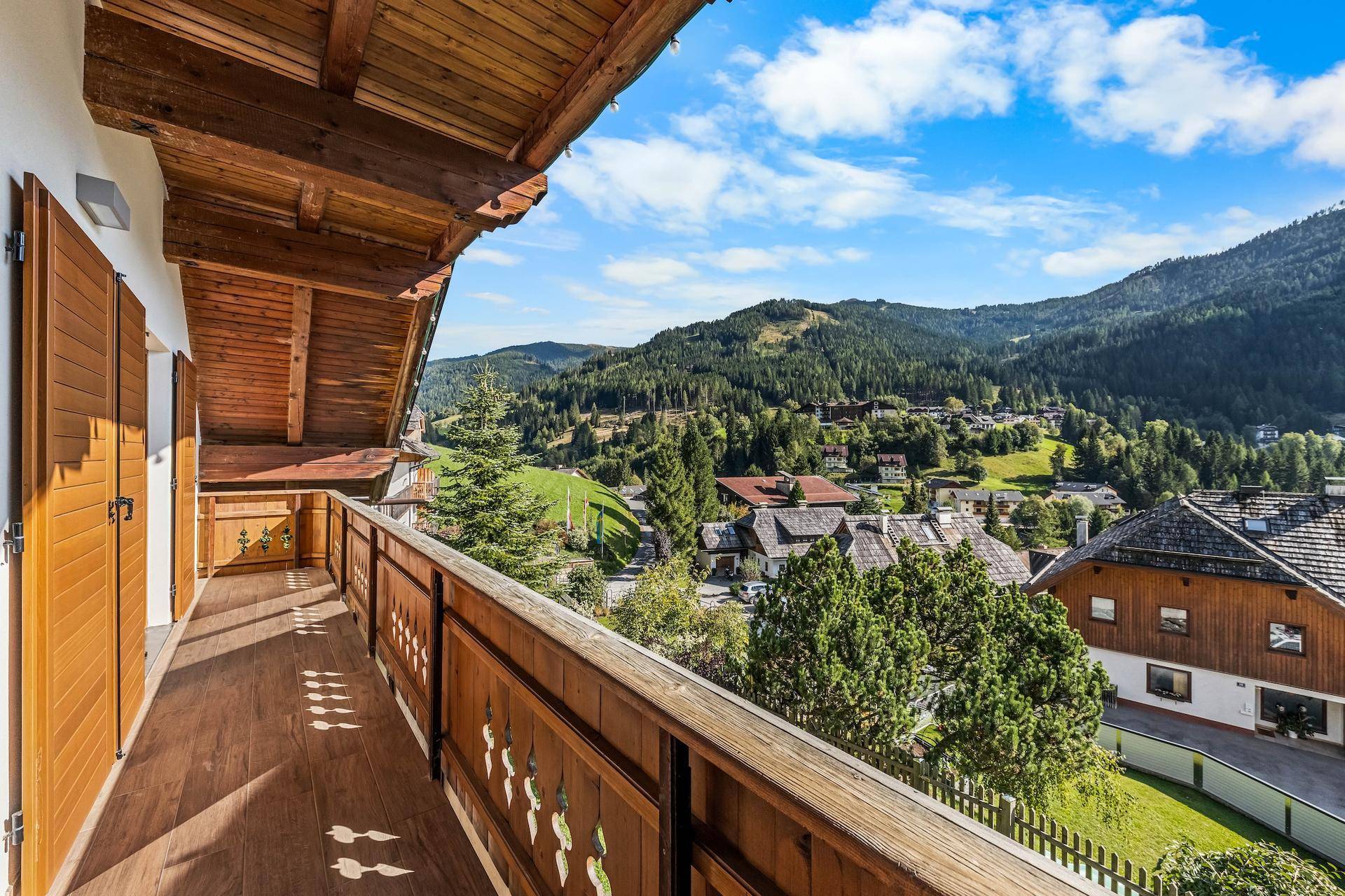 Großer Holzbalkon mit traditionellem Geländer und weitem Blick auf die Berglandschaft.
