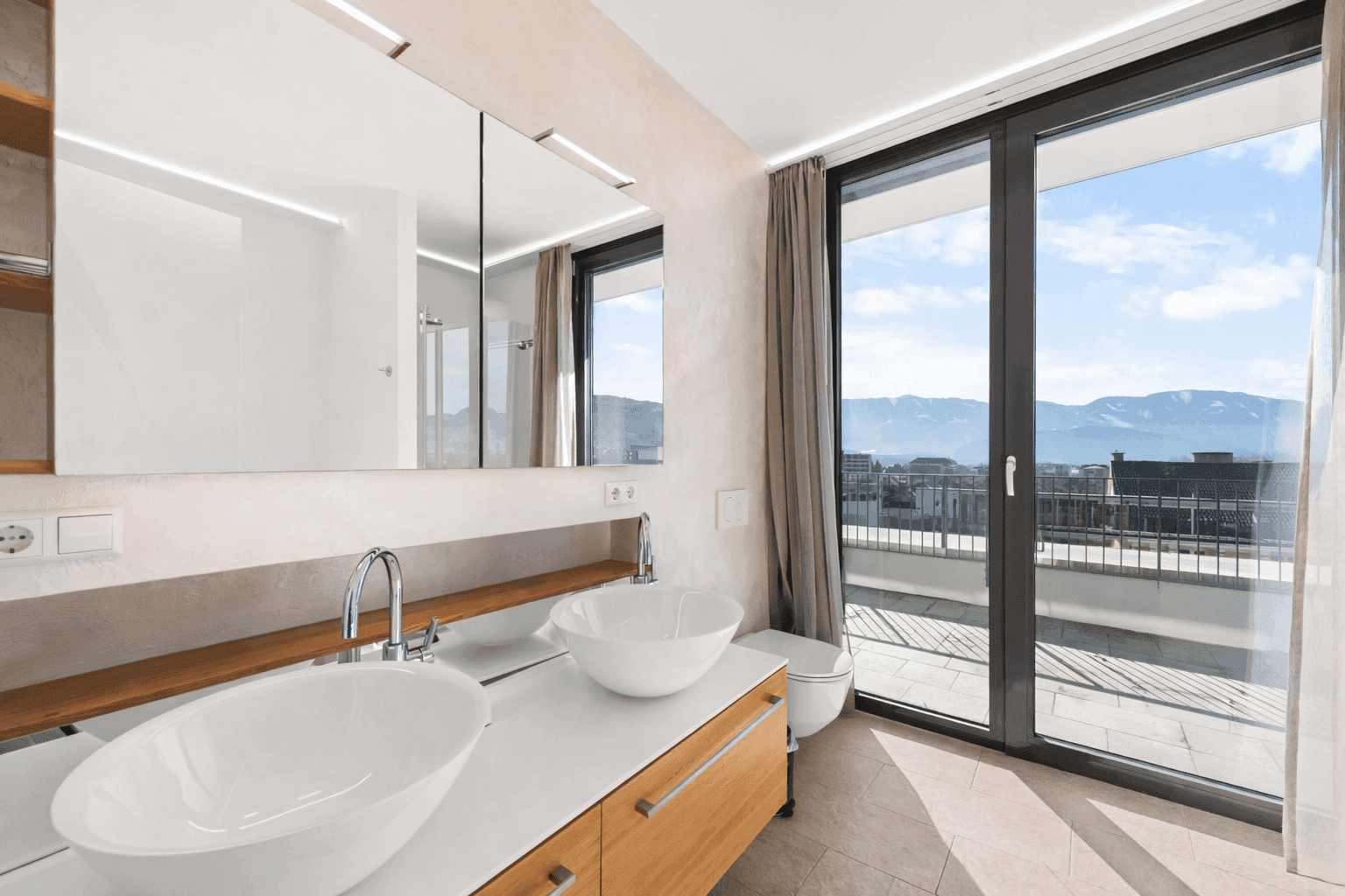 Modernes Badezimmer mit Doppelwaschbecken, Spiegelschrank und Zugang zur Außenterrasse.