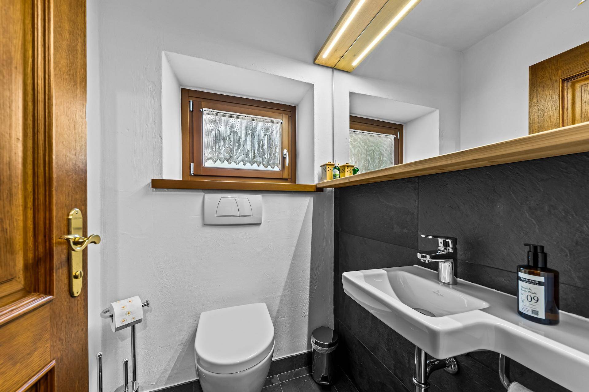 Modernes Gäste-WC mit Fenster, Wand-WC und stilvollem Waschbecken.