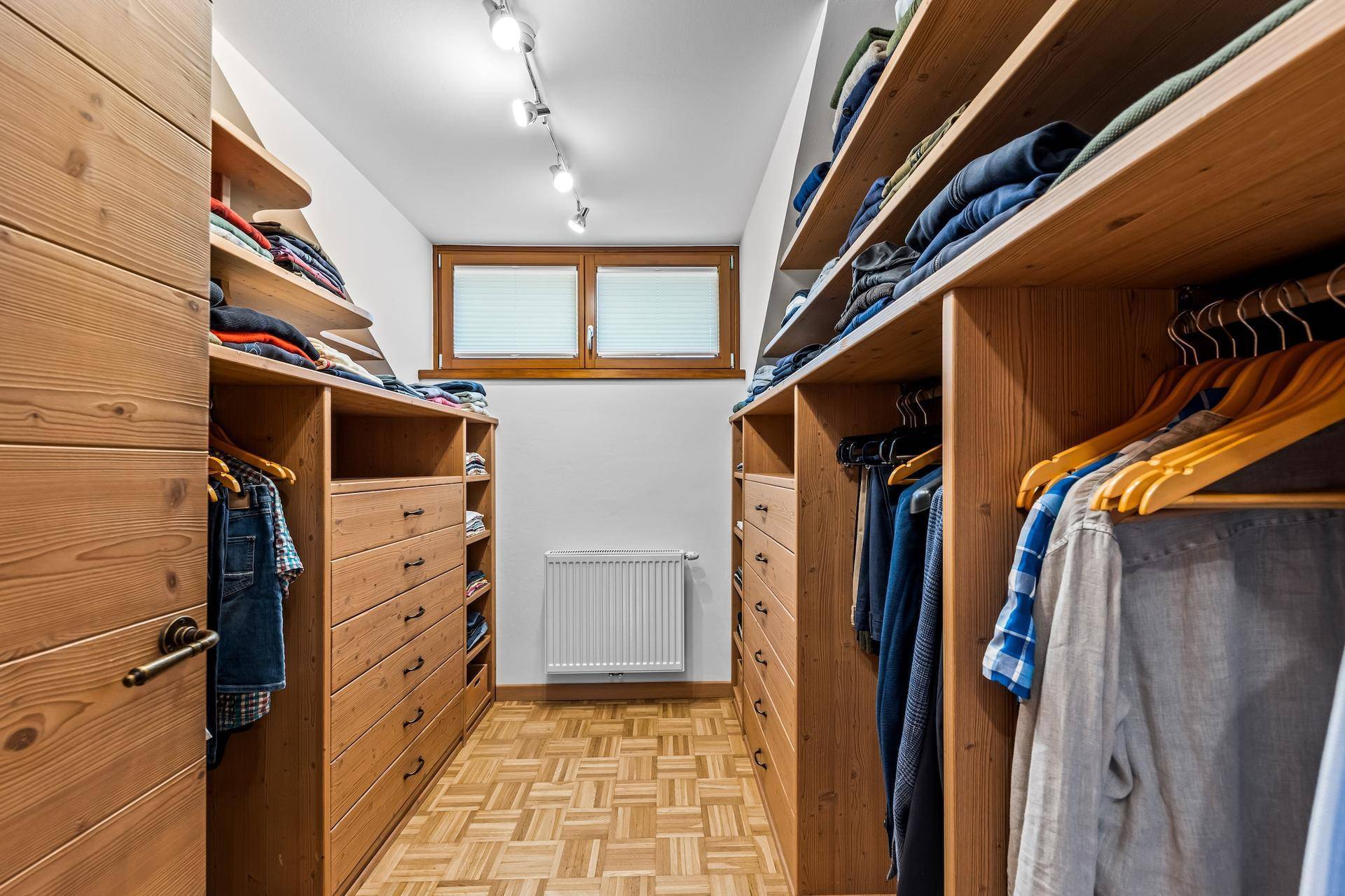 Geräumiger begehbarer Kleiderschrank mit maßgefertigten Holzregalen und viel Stauraum.