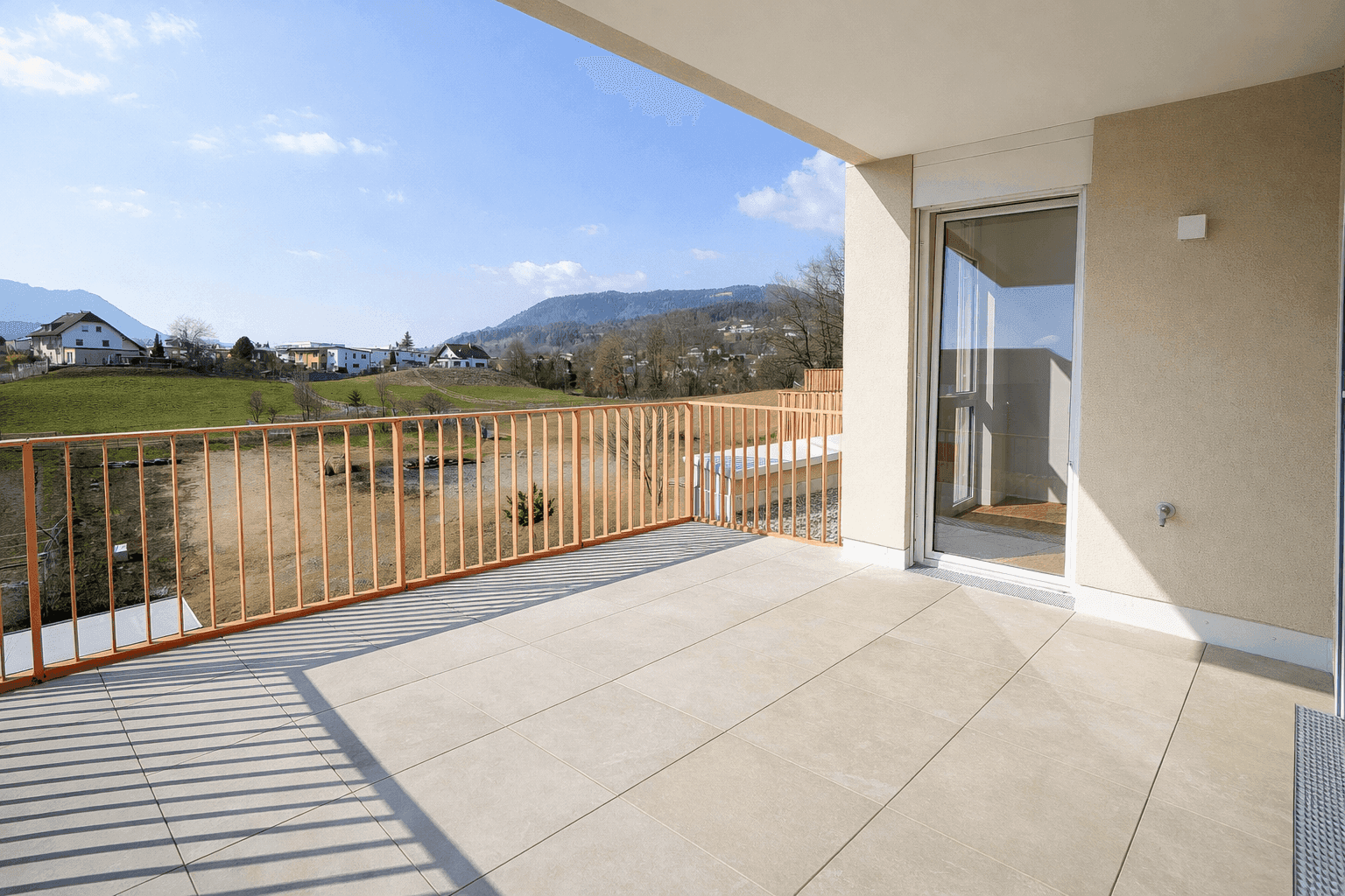Große, sonnige Terrasse mit Fliesenboden und weitem Blick auf die Landschaft.
