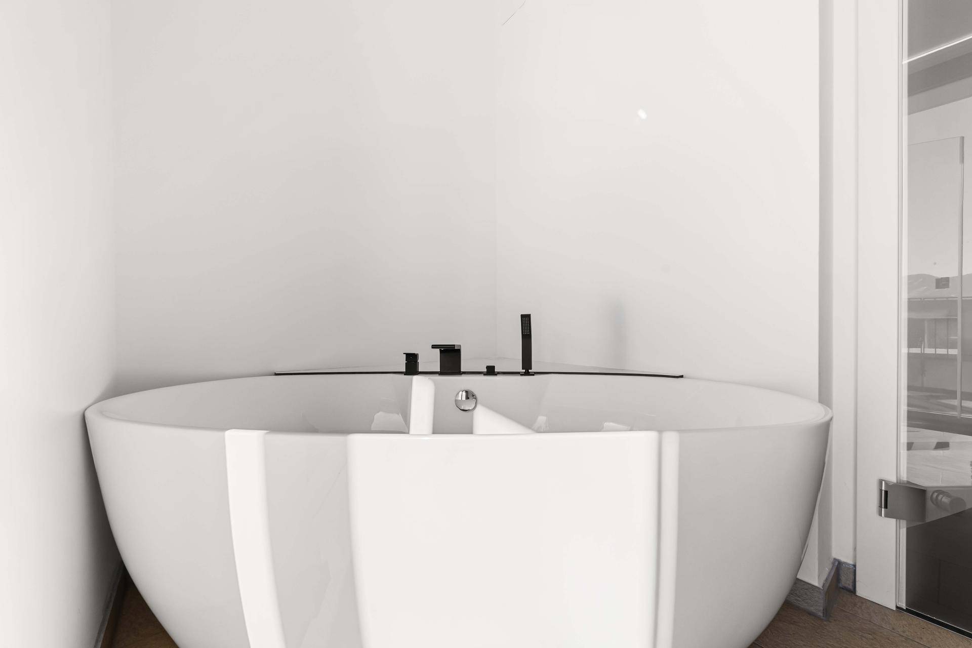 Freistehende Badewanne mit modernen schwarzen Armaturen in einem hellen Badezimmer.