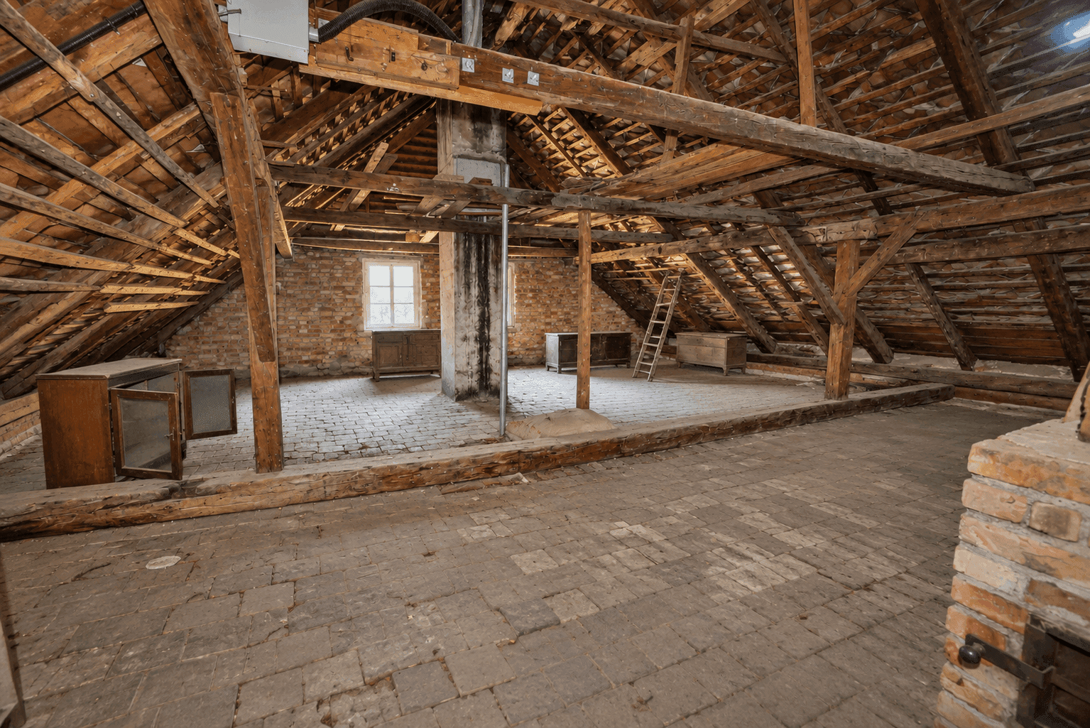 Geräumiger Dachboden mit sichtbaren Holzbalken und Ziegelboden, bietet viel Ausbaupotenzial.