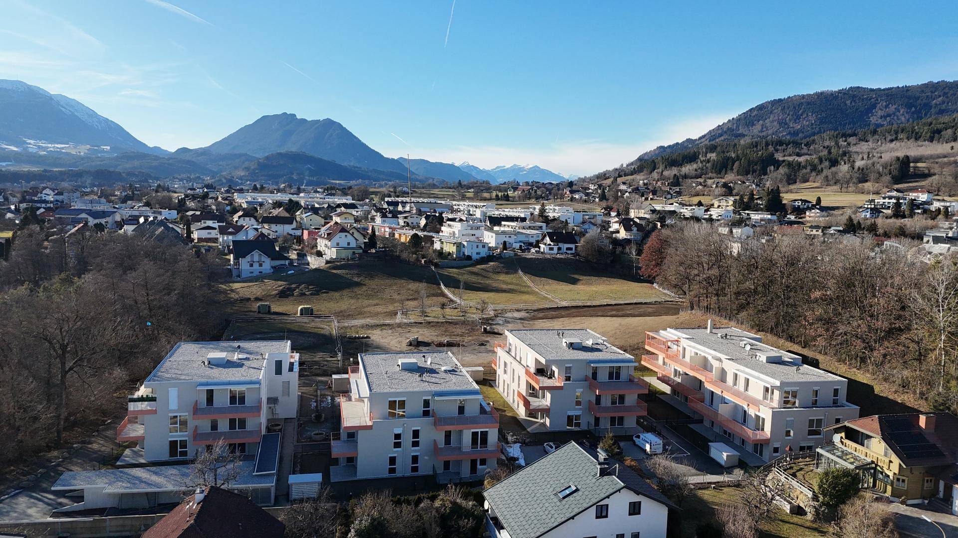 Überblick über die modernen Wohngebäude in einer grünen Landschaft mit Bergen im Hintergrund.