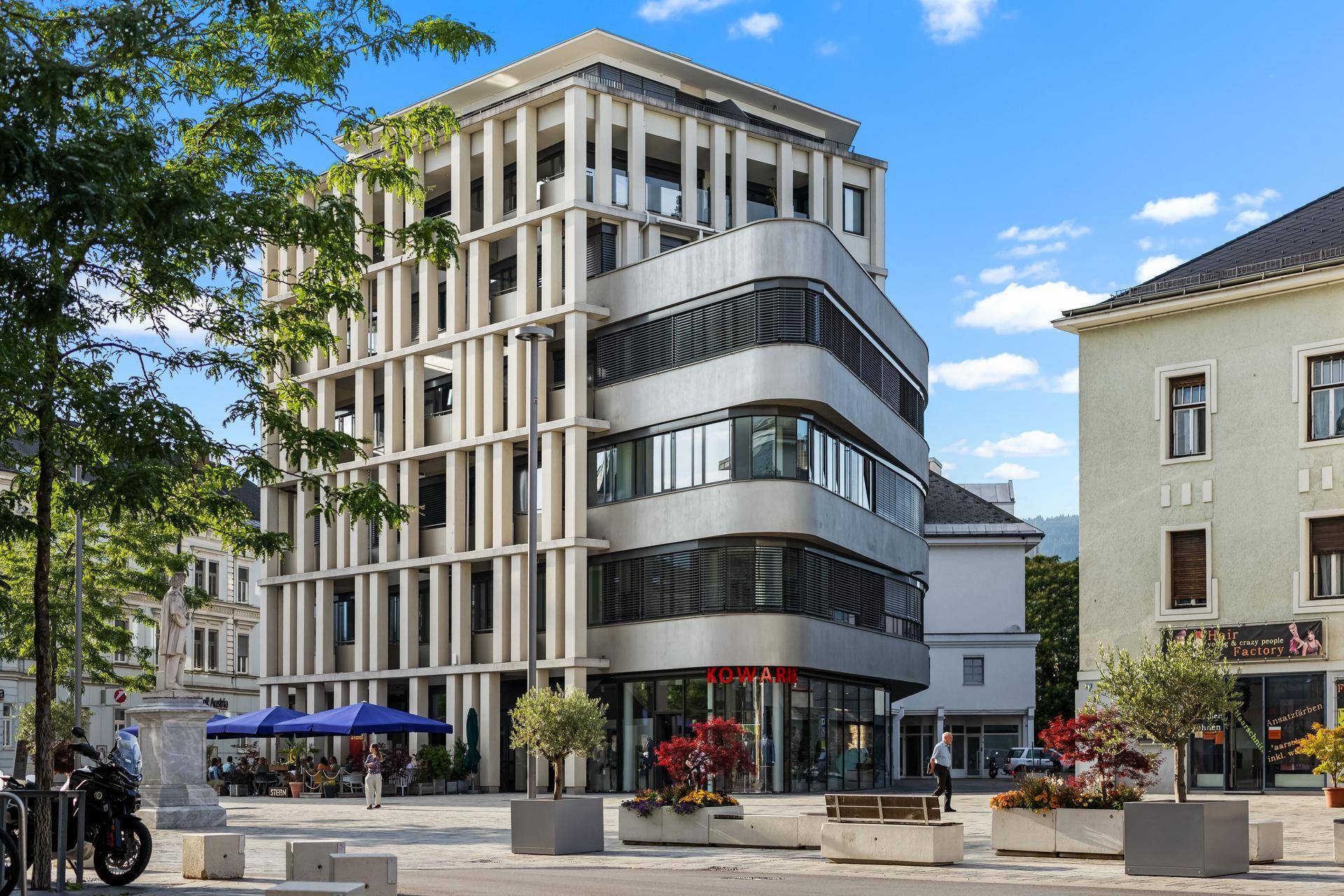 Moderne Architektur eines Gebäudes mit Geschäften im Erdgeschoss und Außenbereich.