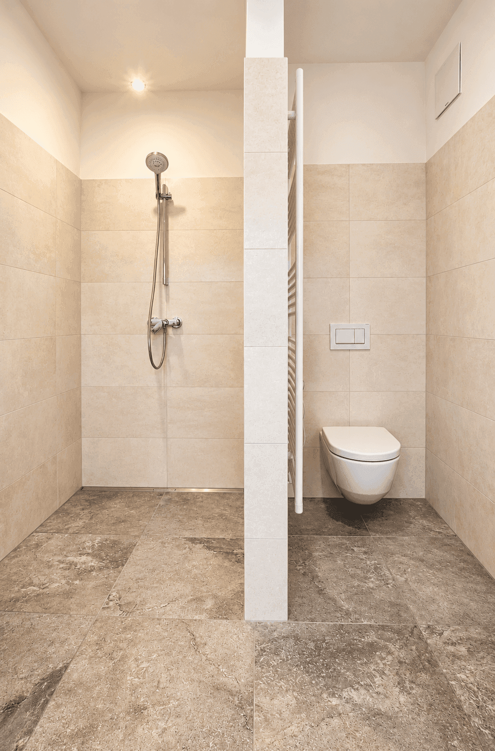 Modernes Badezimmer mit ebenerdiger Dusche und wandhängendem WC, in hellen Fliesen gehalten.