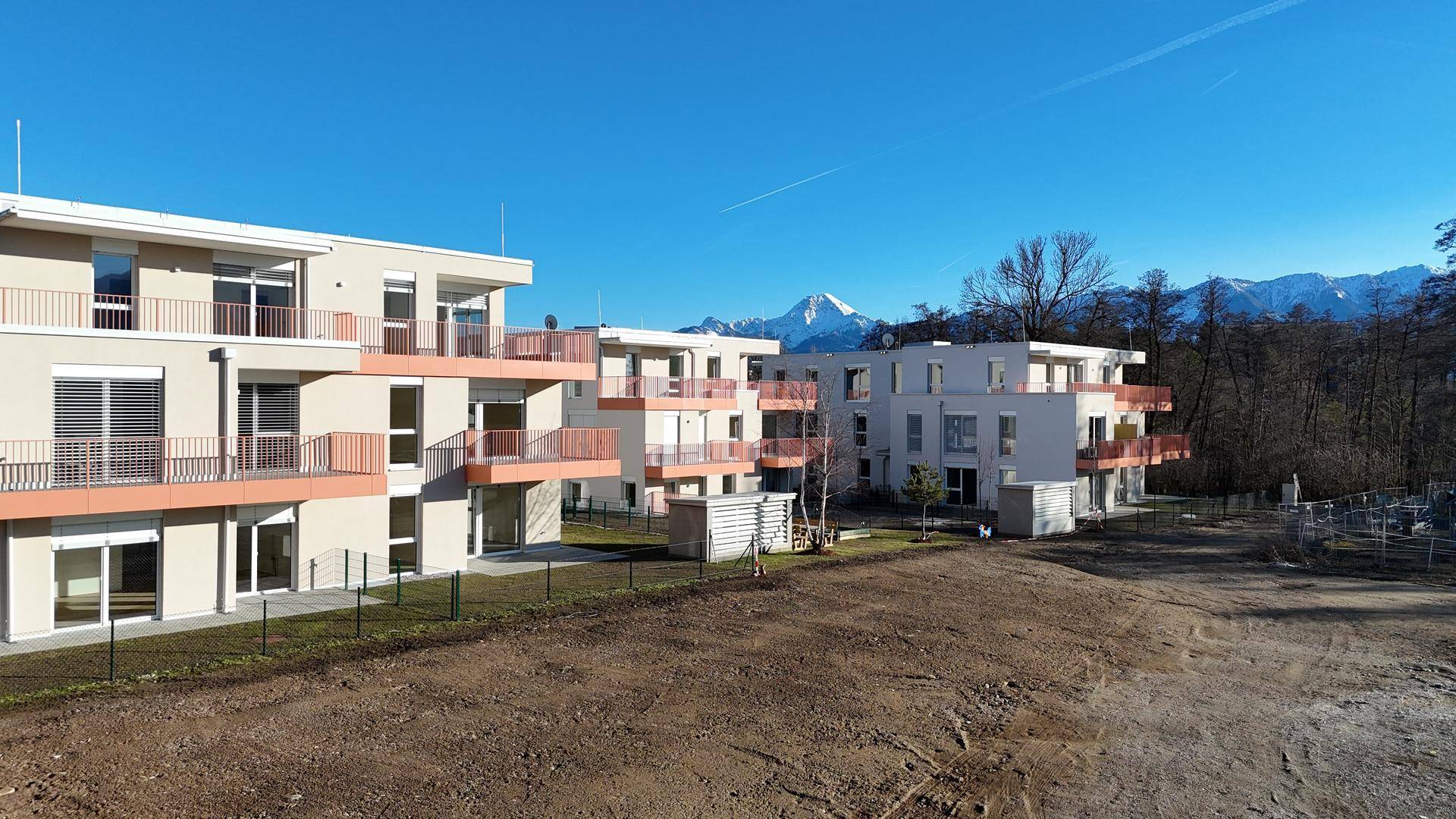 Neue Wohngebäude mit Balkonen und Blick auf die schneebedeckten Berge im Hintergrund.