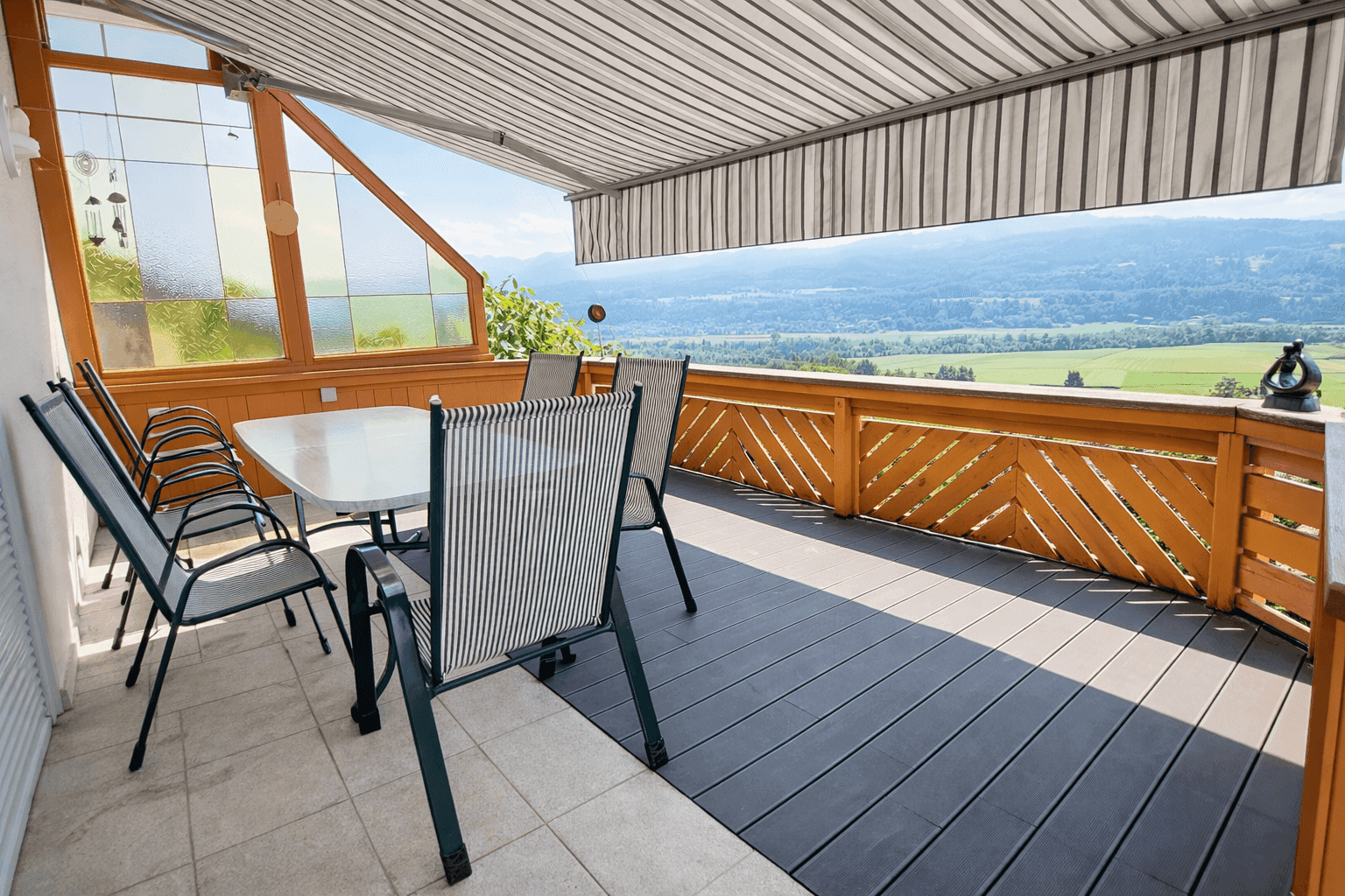 Große Terrasse mit Markise, Gartenmöbeln und weitem Blick über die Landschaft.