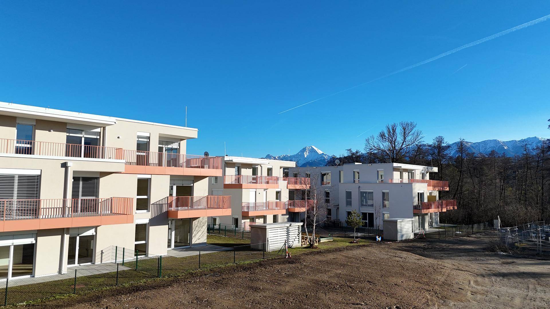 Luftaufnahme einer modernen Wohnanlage mit mehreren Gebäuden und Bergblick.