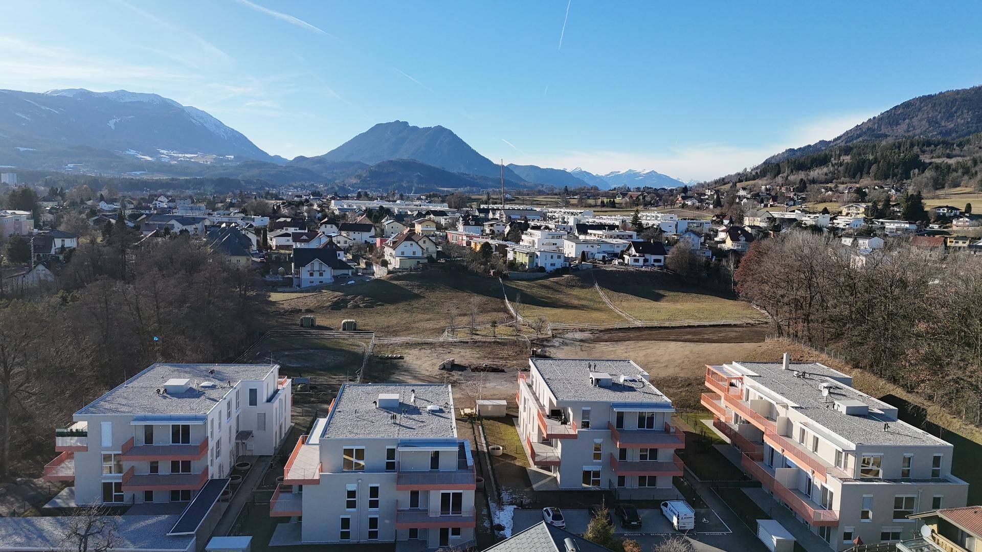 Weitläufige Luftaufnahme einer Wohnanlage in ländlicher Umgebung mit Bergblick.