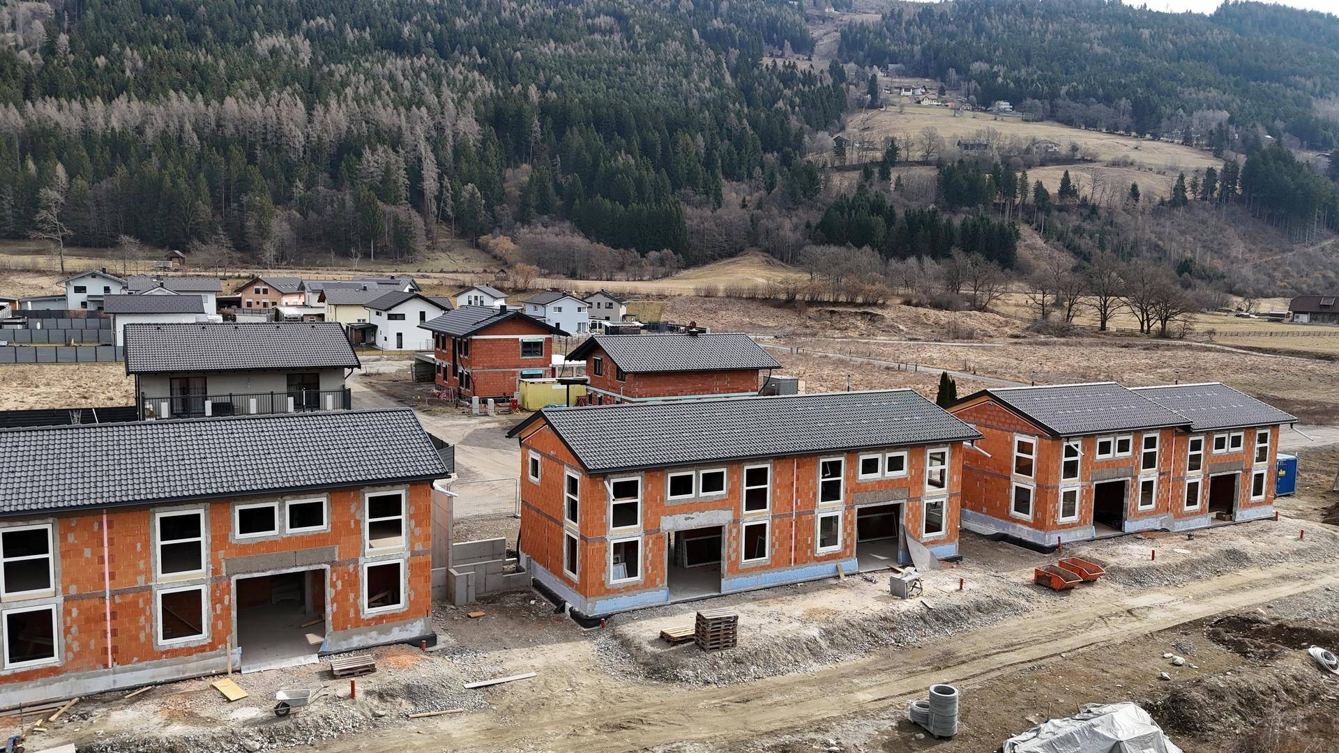 Luftaufnahme einer Neubausiedlung mit mehreren im Bau befindlichen Reihenhäusern in ländlicher Umgebung.