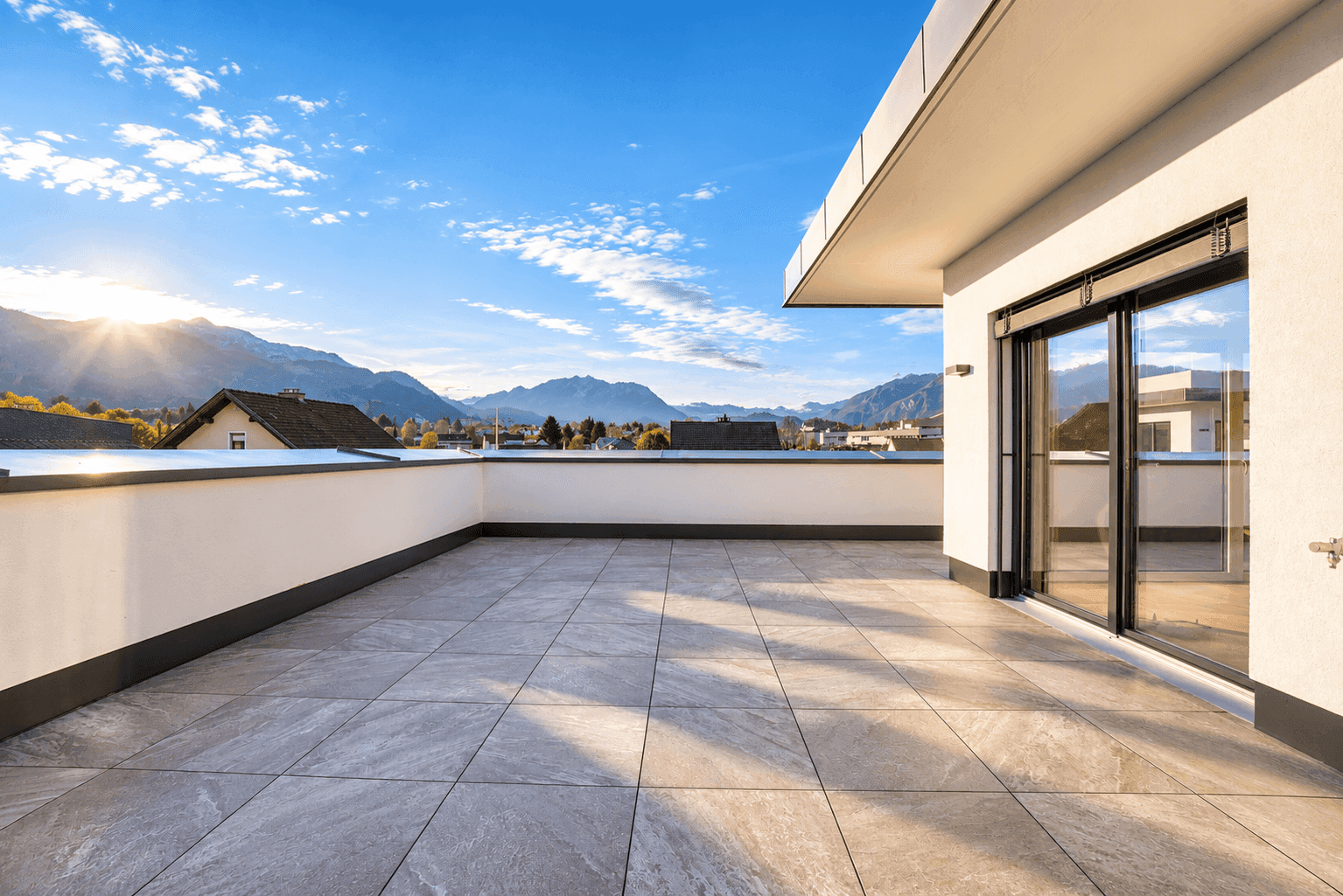 Geräumige, unmöblierte Dachterrasse mit Fliesenboden und weitem Blick auf die Berge.
