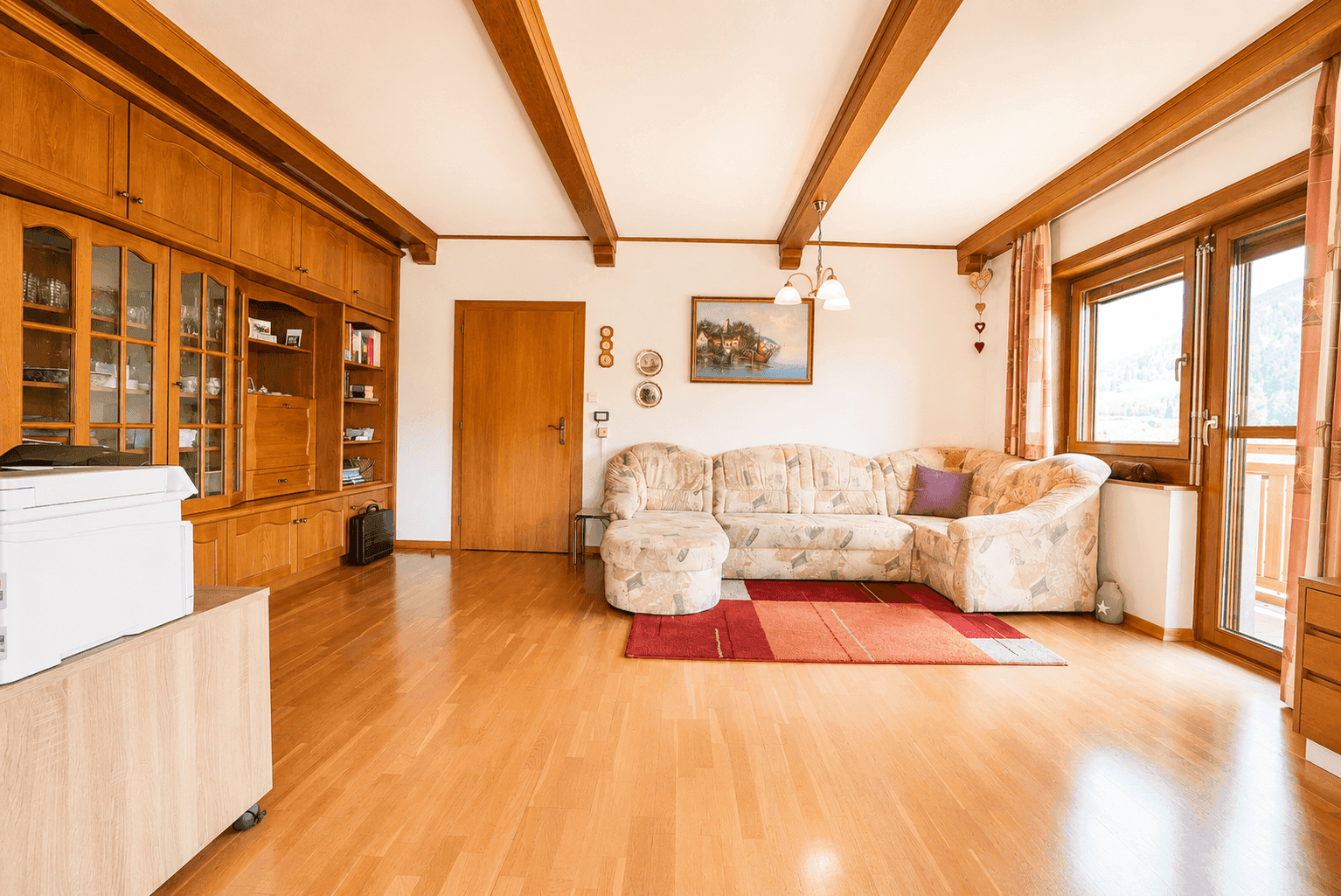 Gemütliches Wohnzimmer mit Holzbalken, Parkettboden und traditionellen Holzmöbeln.