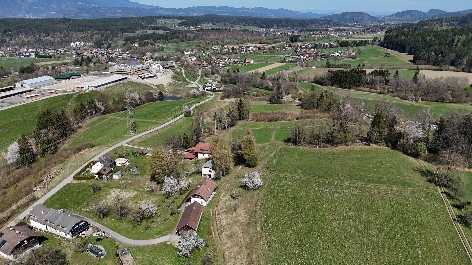 Weitläufige Luftaufnahme einer ländlichen Siedlung mit Feldern, Häusern und Industriegebäuden unter klarem Himmel.