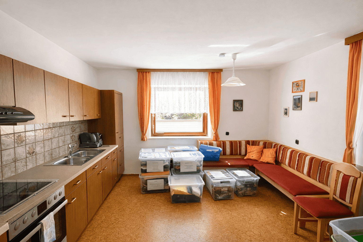 Geräumige Wohnküche mit Holzschränken, Linoleumboden und einer gemütlichen Eckbank.