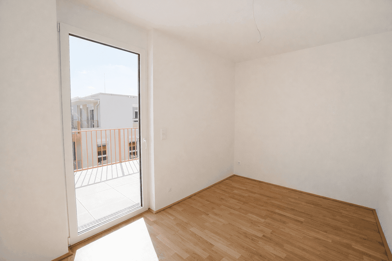 Schlafzimmer mit Parkettboden und direktem Zugang zu einem sonnigen Balkon.