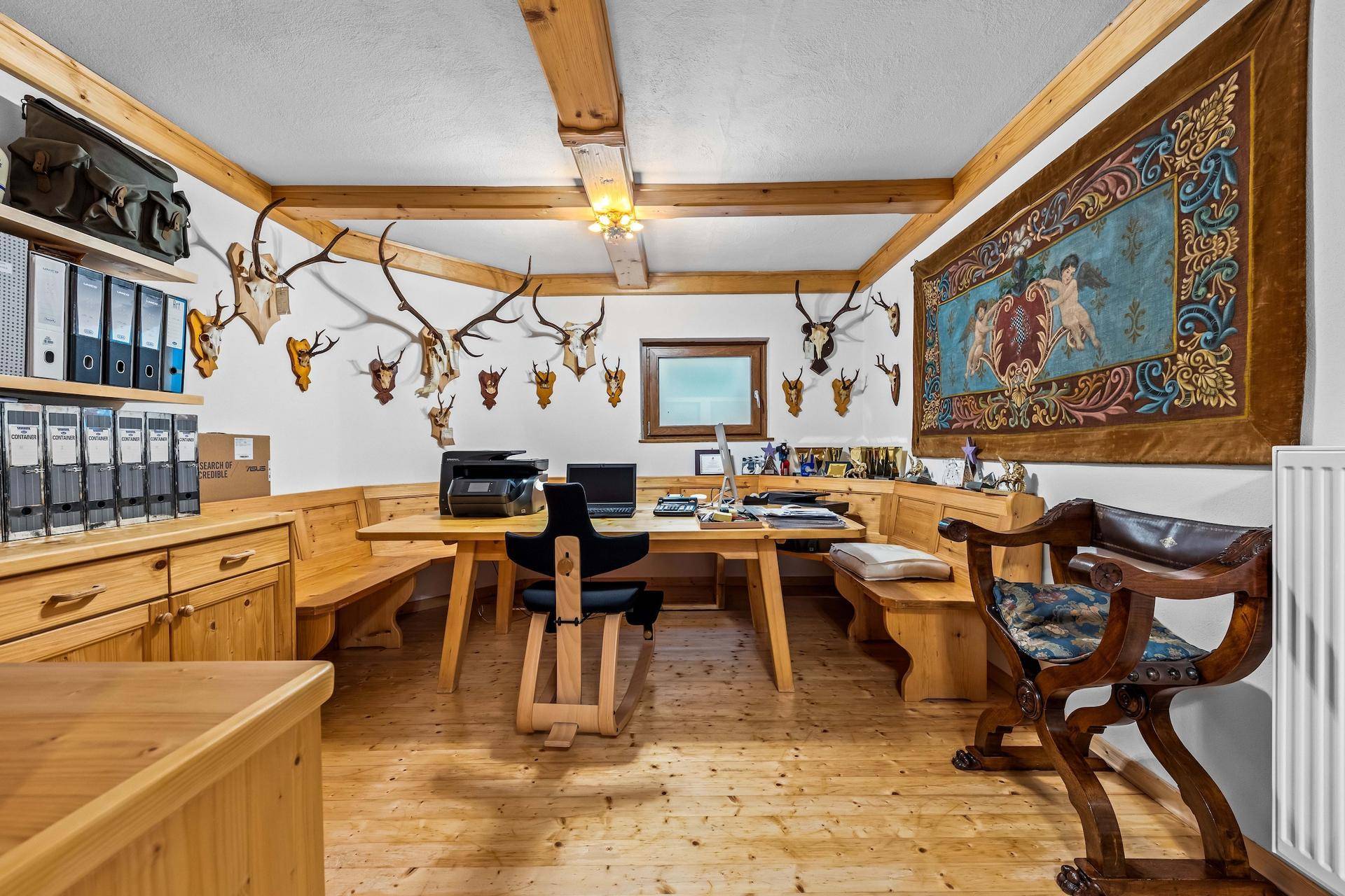Geräumiges Büro mit Holzboden, Holzbalken und traditioneller Jagdtrophäen-Dekoration.