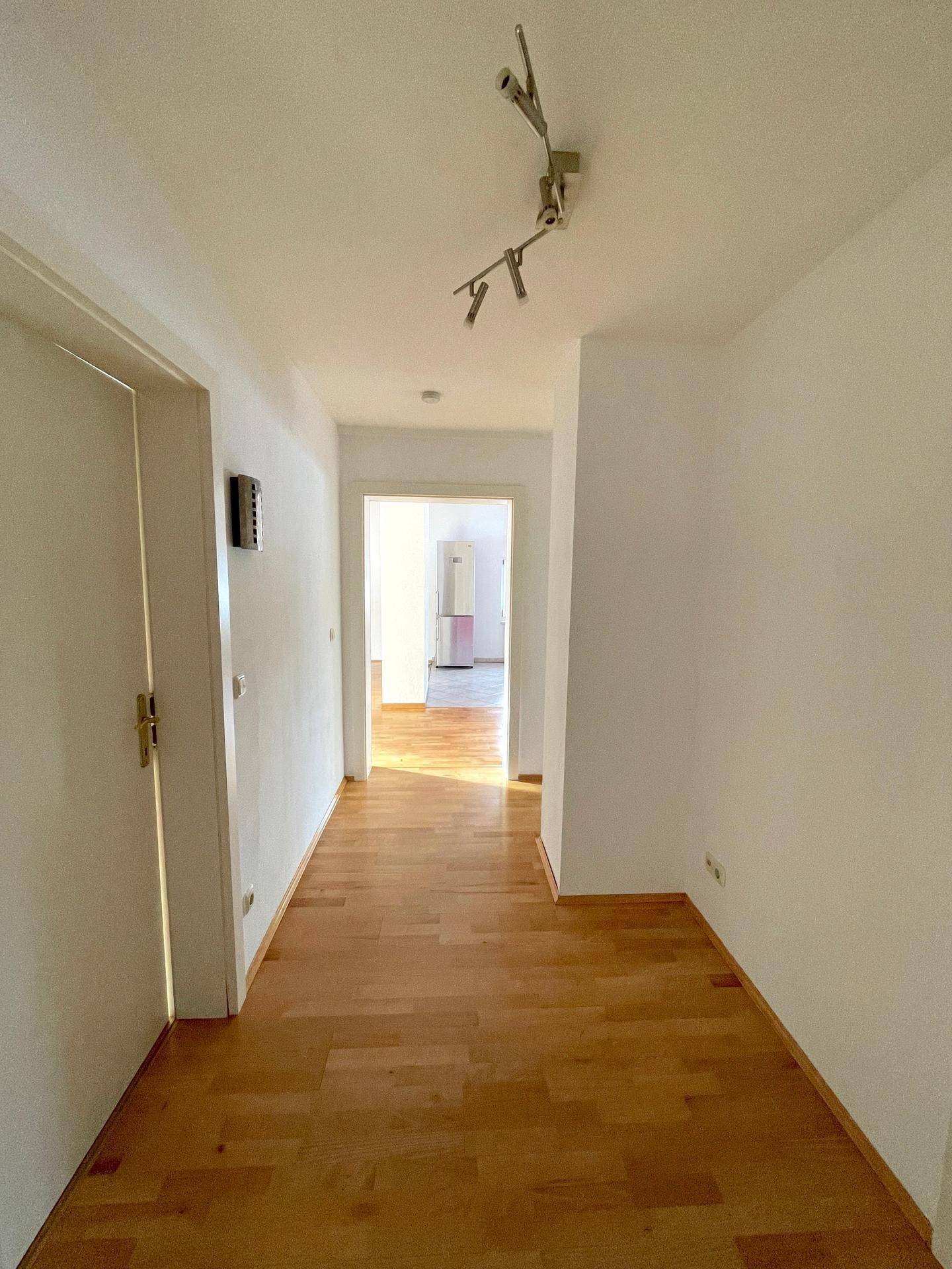 Heller Flur mit Holzboden, der zu den verschiedenen Zimmern der Wohnung führt.