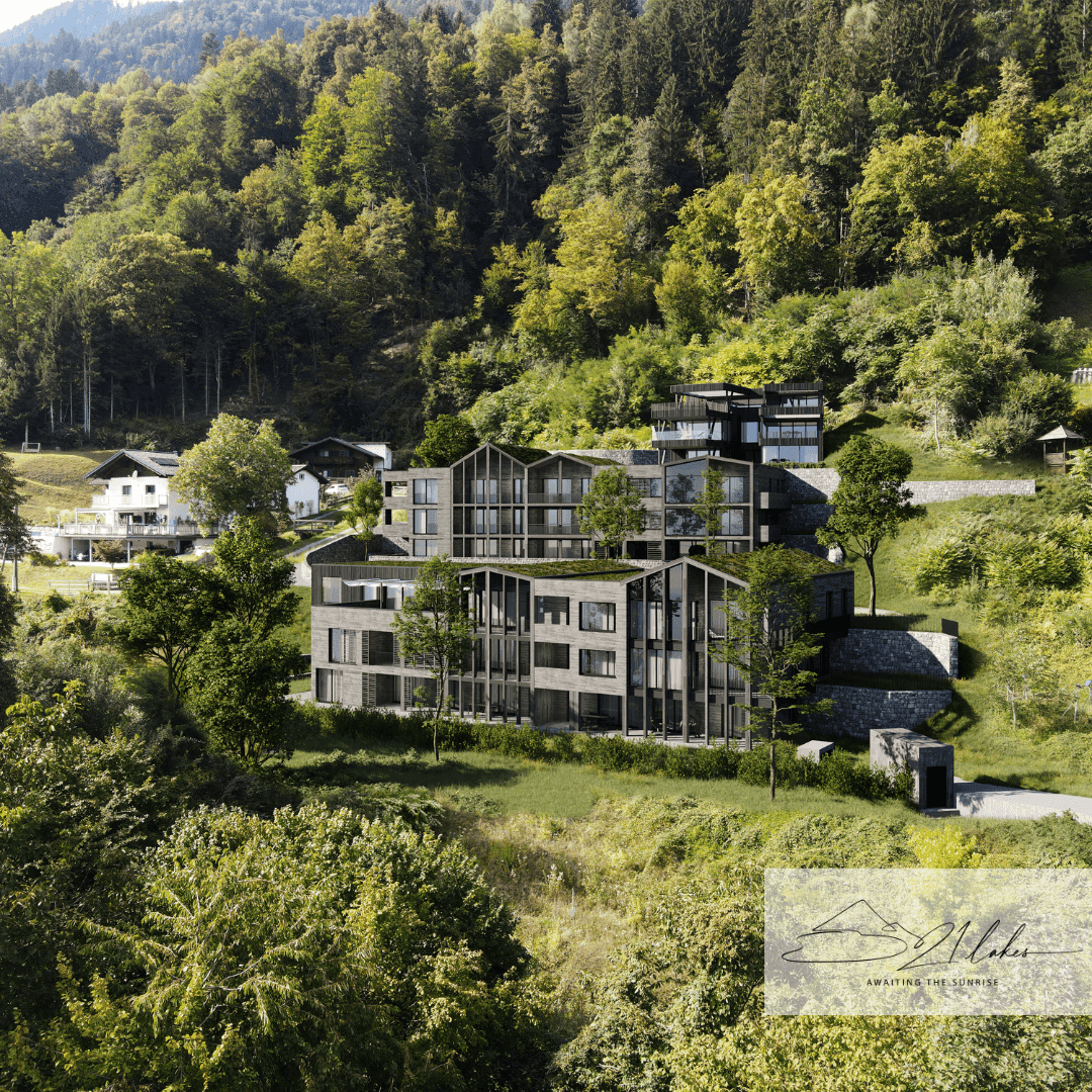Luftaufnahme einer modernen Wohnanlage mit mehreren Gebäuden in einer grünen, hügeligen Landschaft.