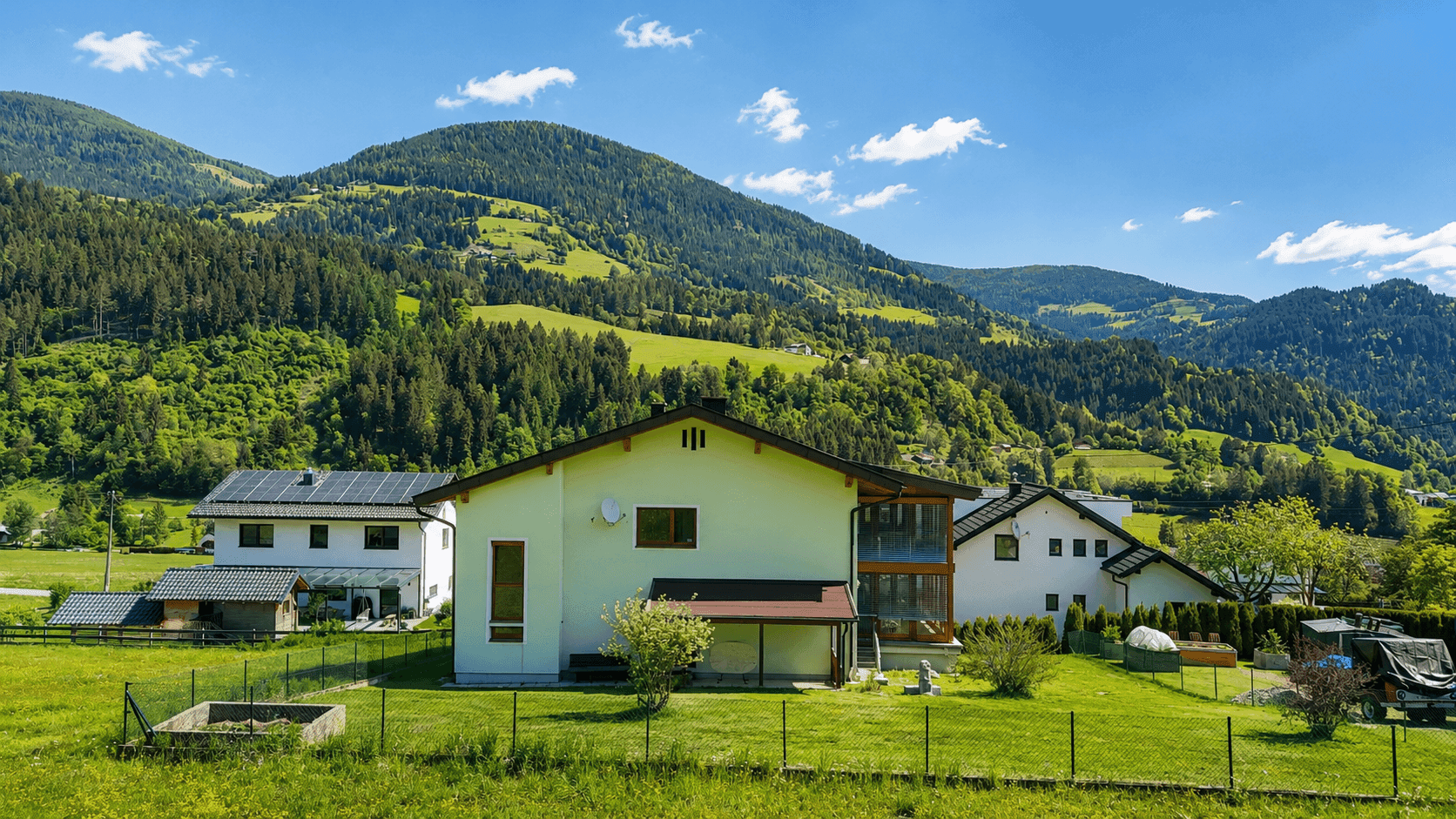 Freistehendes Haus mit Balkon und Garten, eingebettet in eine grüne Berglandschaft.