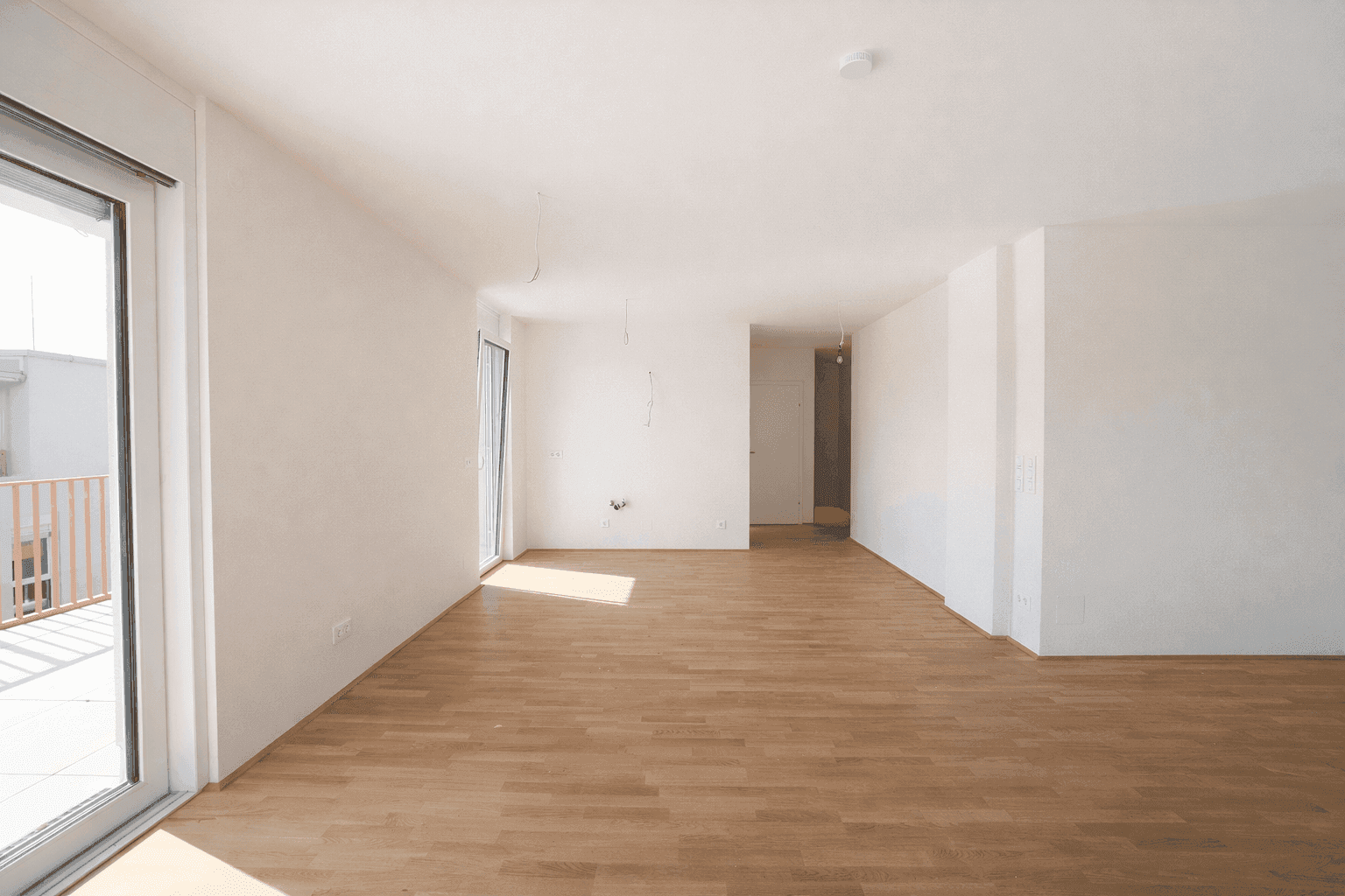 Geräumiger, heller Wohnraum mit Parkettboden und direktem Zugang zu einer Terrasse.