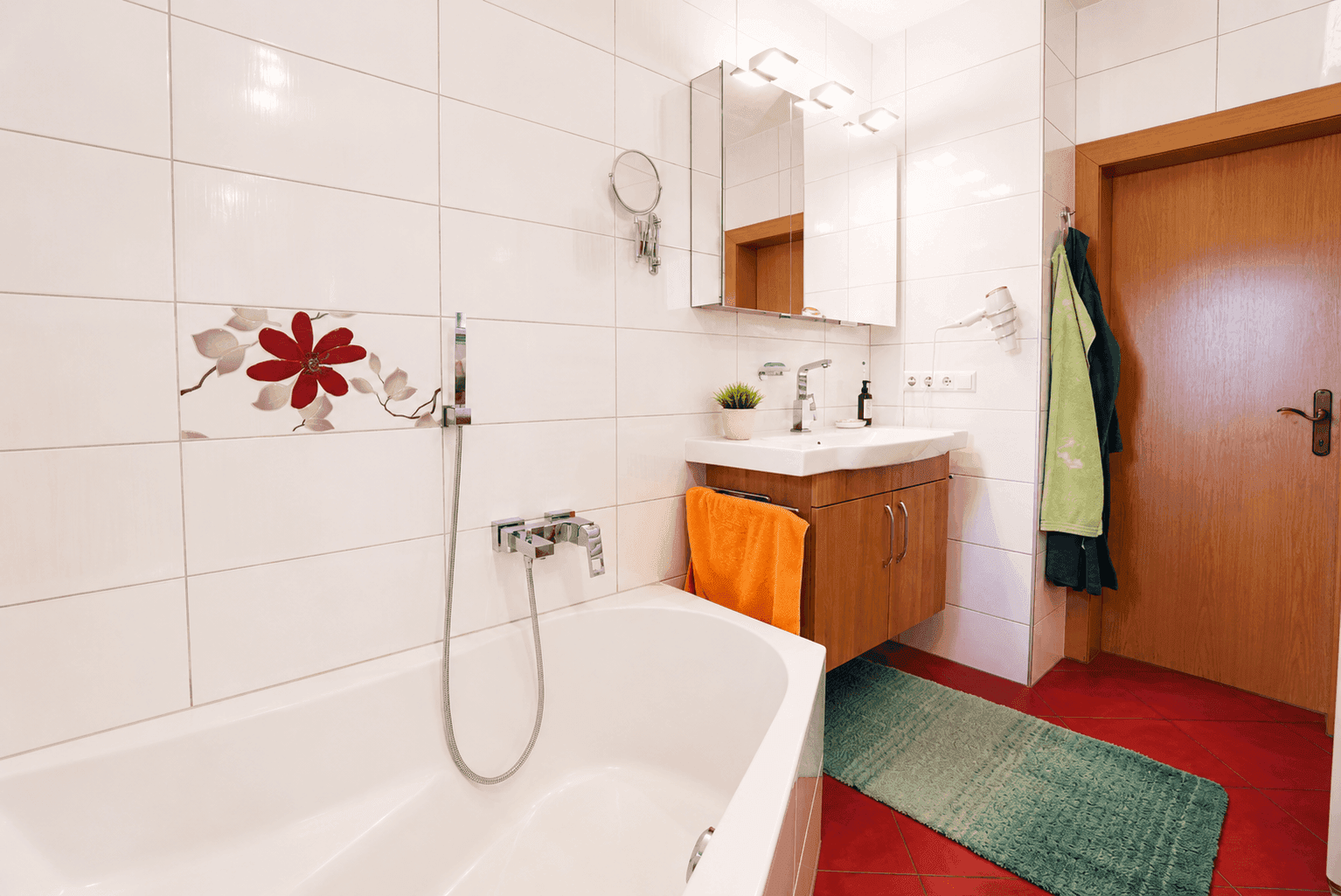Traditionelles Badezimmer mit Badewanne, Waschtisch und floralen Akzentfliesen.
