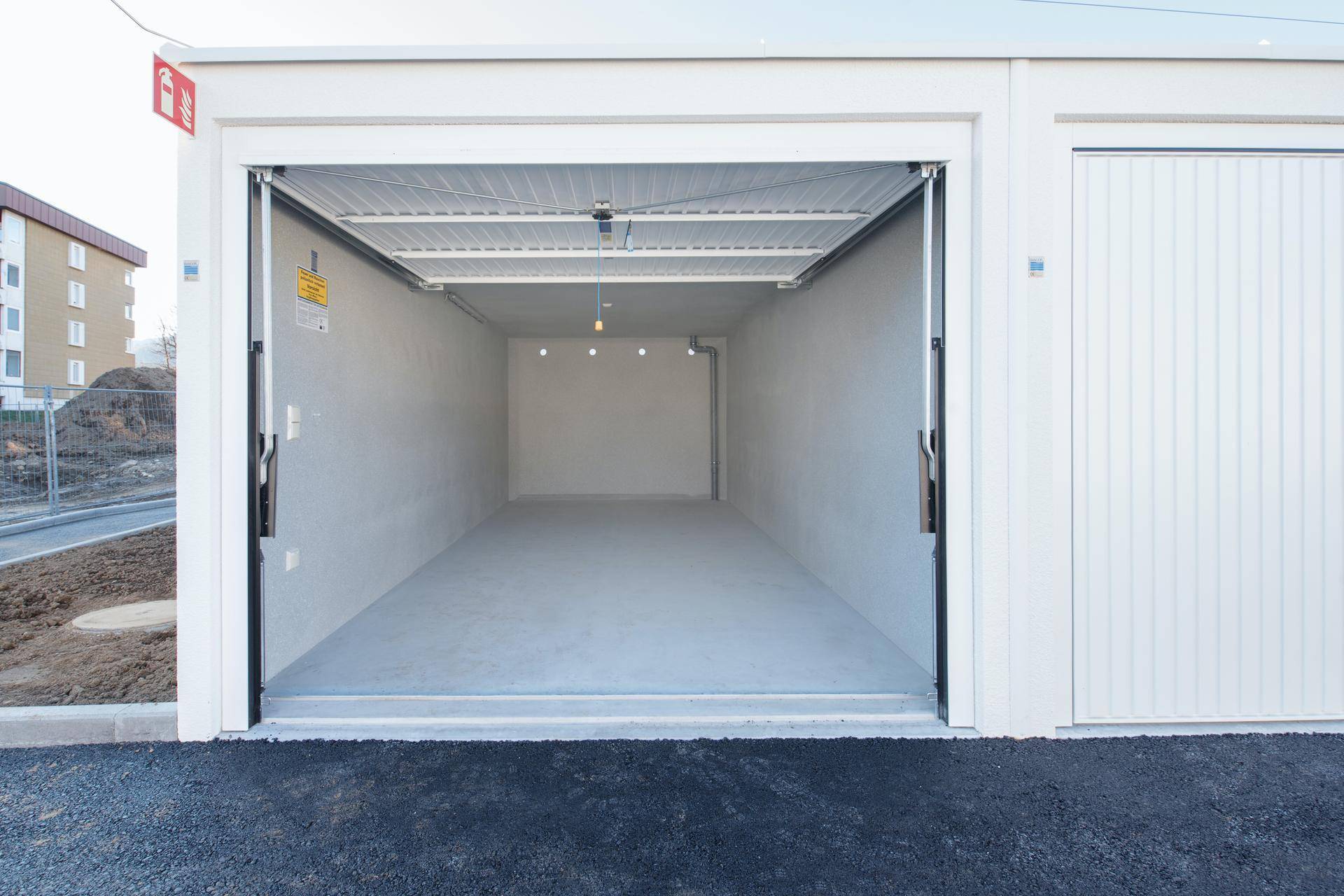 Leere, neuwertige Garage mit Betonboden und weiß gestrichenen Wänden, bereit zur Nutzung.