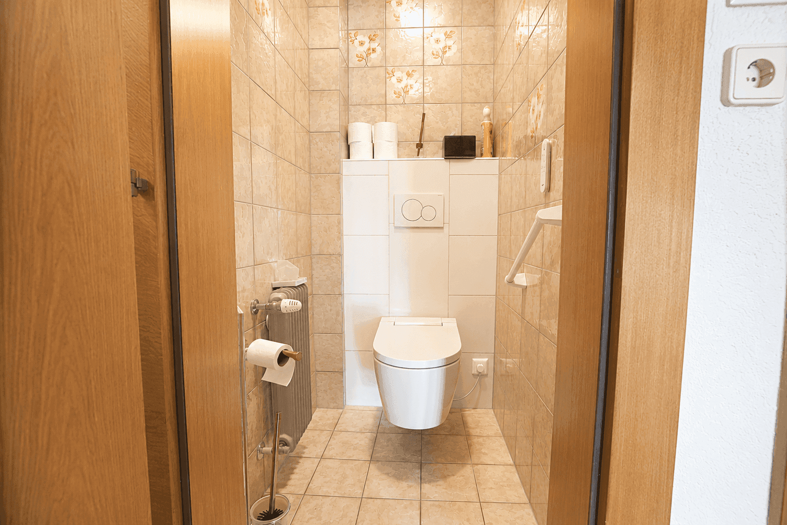 Separates Gäste-WC mit Wand-WC, Fliesenboden und Heizkörper.