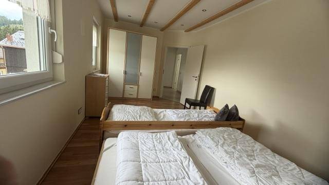Helles Schlafzimmer mit zwei Einzelbetten, Kleiderschrank und Holzboden.