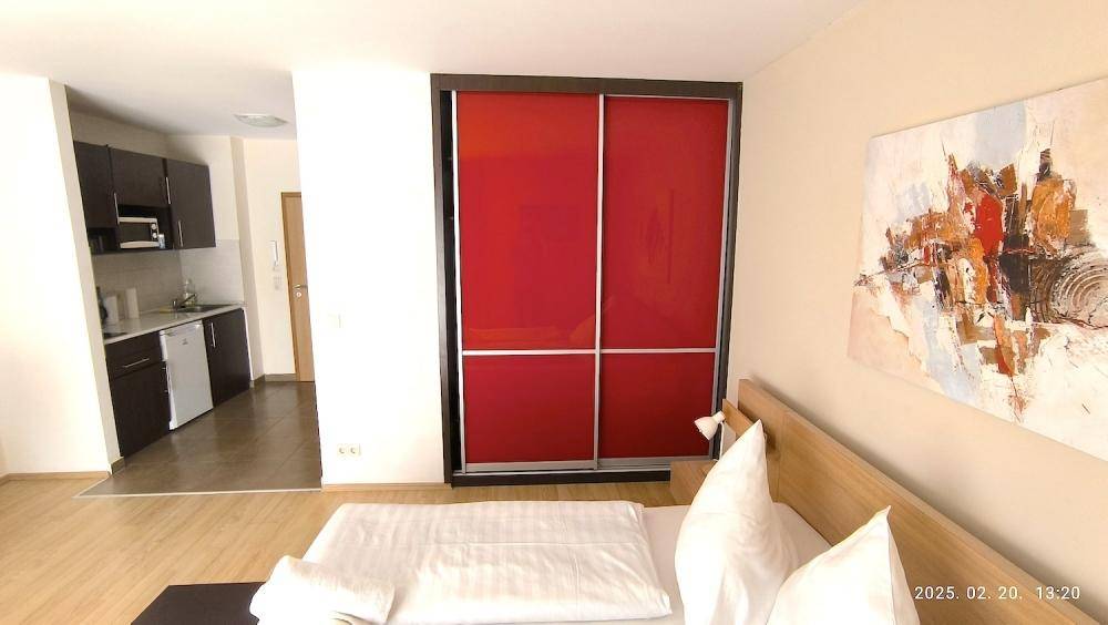 Schlafzimmer mit Doppelbett und Blick auf die angrenzende, funktionale Küchenzeile.