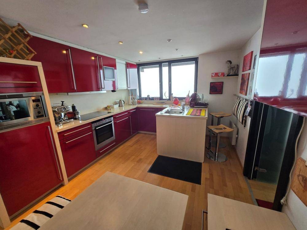 Moderne Küche mit roten Hochglanzfronten, Holzboden und integrierten Geräten.