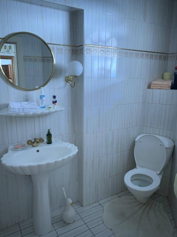 Kleines WC mit Standwaschbecken, Toilette und runden Spiegel.