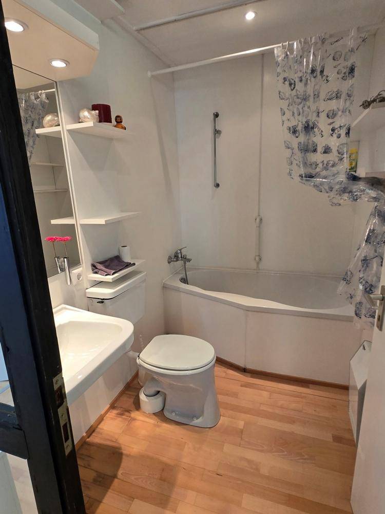 Badezimmer mit Badewanne, WC, Waschbecken und Holzboden.