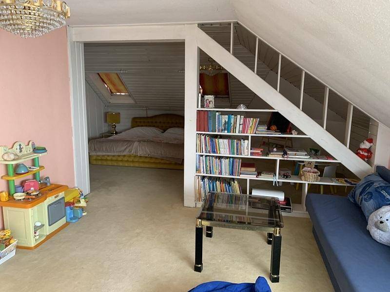 Geräumiger Dachbodenbereich mit Stauraum, Bücherregal und Schlafbereich.