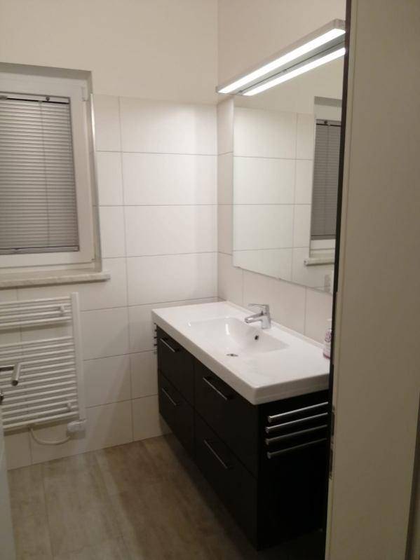Modernes Badezimmer mit Waschbecken, Spiegel, Fenster und beheiztem Handtuchhalter.