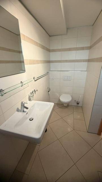 Funktionales Badezimmer mit WC, Waschbecken und hellen Fliesen, sauber und gepflegt.